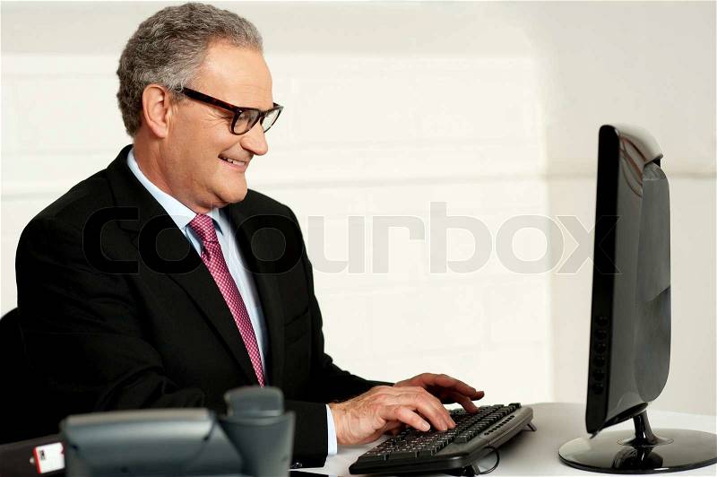 Cheerful aged man working on computer, stock photo