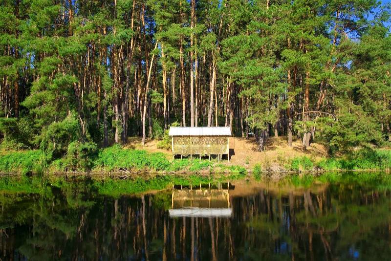 Beautiful countryside wooden house on the lake in a pine forest. Place of rest and fishing, stock photo