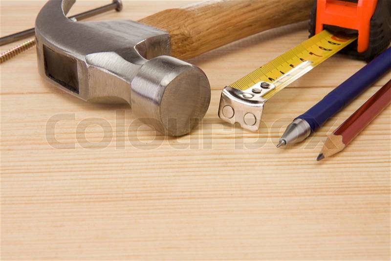 Hammer, tape measure, nail and pencil on wood, stock photo