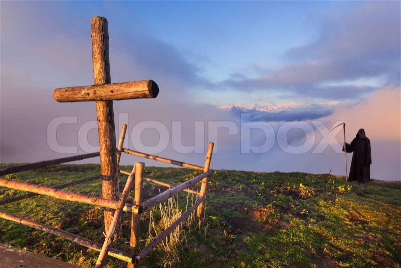 Catholic cross on a mountaintop and death that stands apart, stock photo