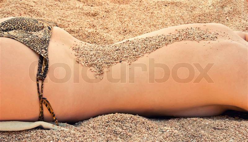 Woman lying on the beach with sand on her back, stock photo