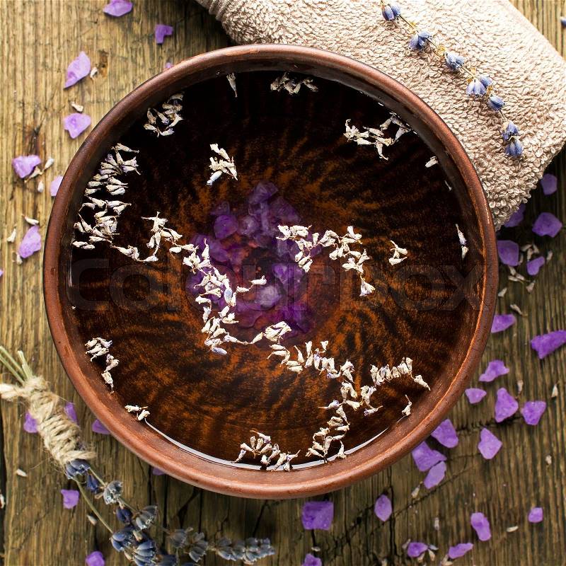 Bowl of pure water and lavender petals on the old wooden surface. Spa treatments composition, stock photo