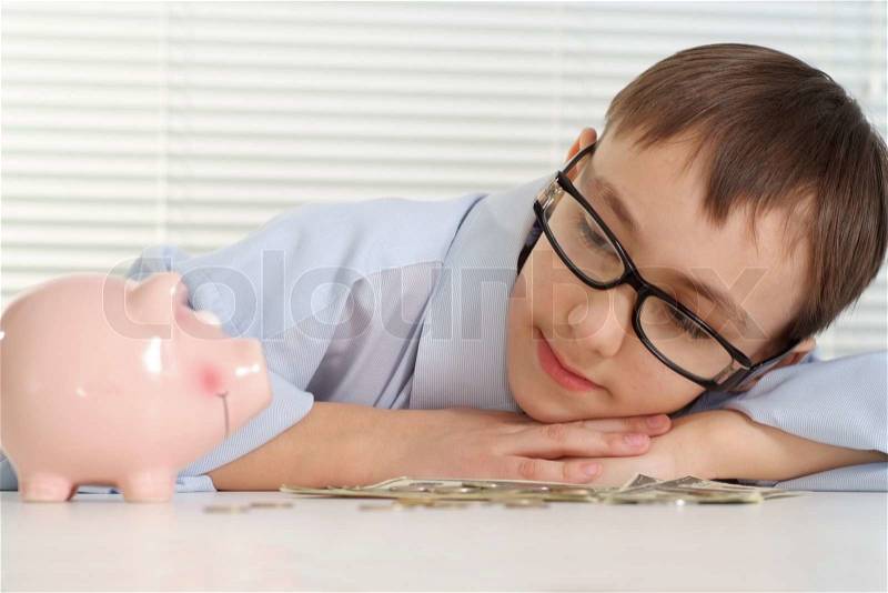 A young Caucasian good business man is looking at a piggy bank, stock photo