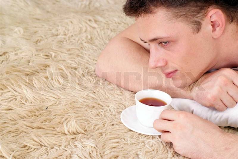 Pretty Caucasian male lying on a rug, stock photo
