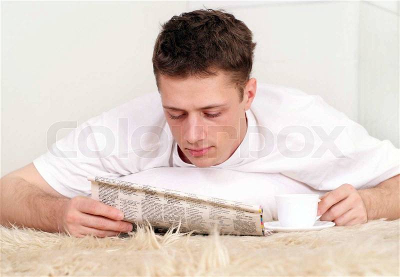 Beautiful Caucasian man lying on the mat with the paper, stock photo