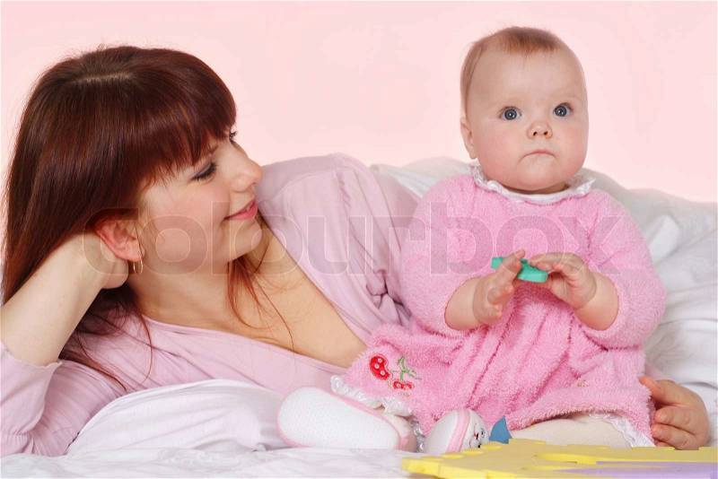A beautiful nice mother with her daughter lying in bed, stock photo