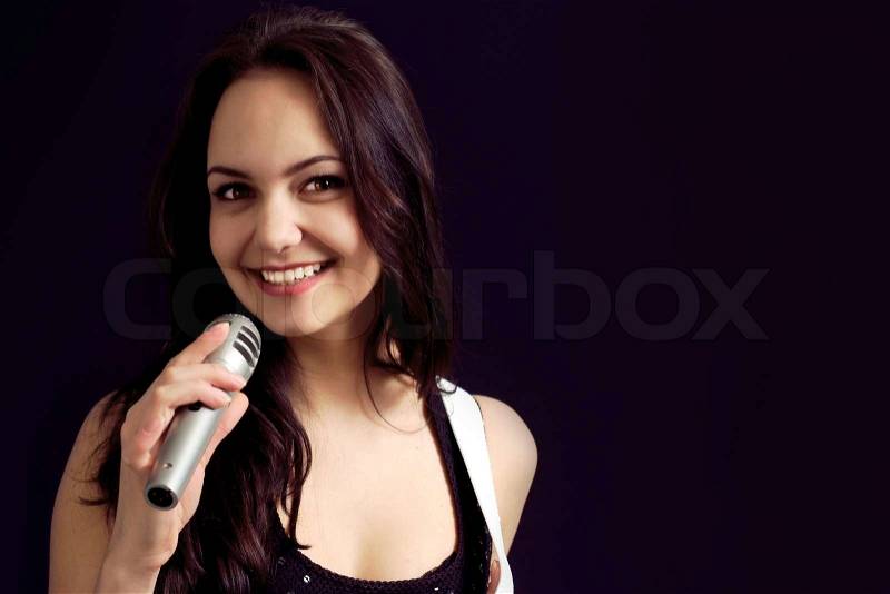 Pretty Caucasian young woman posing with a microphone, stock photo
