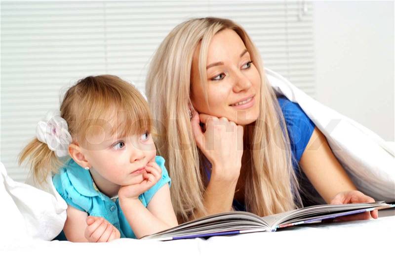 Good caucasian mother and daughter lying with a book, stock photo