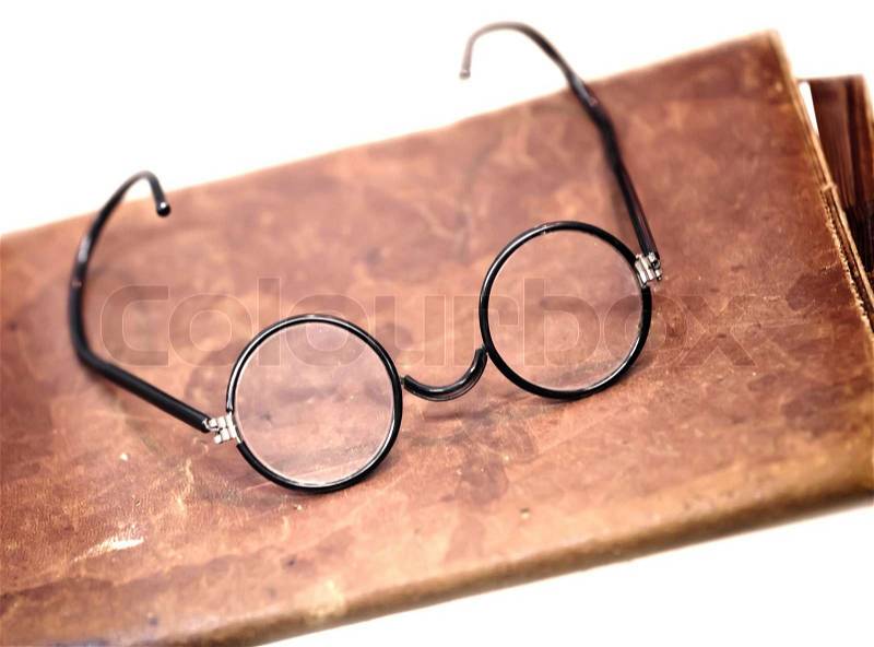 Old glasses on the leather folder isolated on white, stock photo