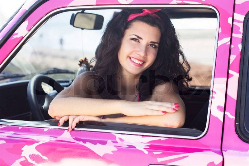 Beautiful woman sitting in the pink car, stock photo