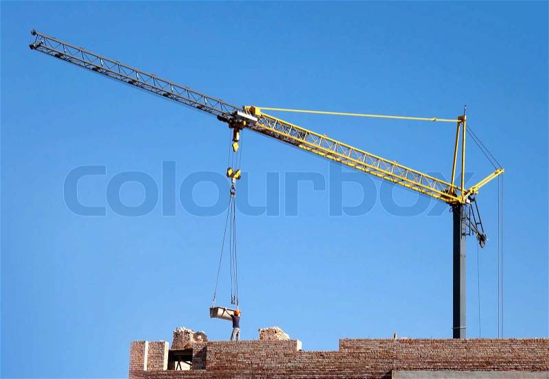 Small tower crane and top of new brick building, stock photo