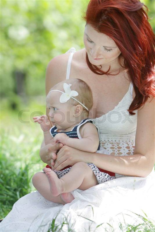 Young happy mother and baby girl on natural background, stock photo