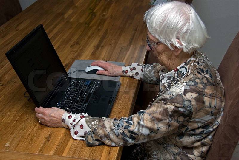 Older senior woman above eighty years old working with a laptop computer, stock photo