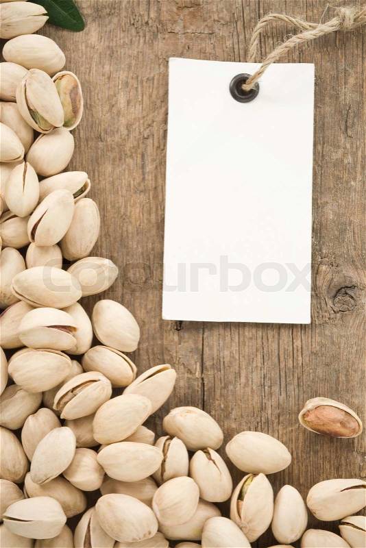 Pistachios and tag paper label on wood background, stock photo