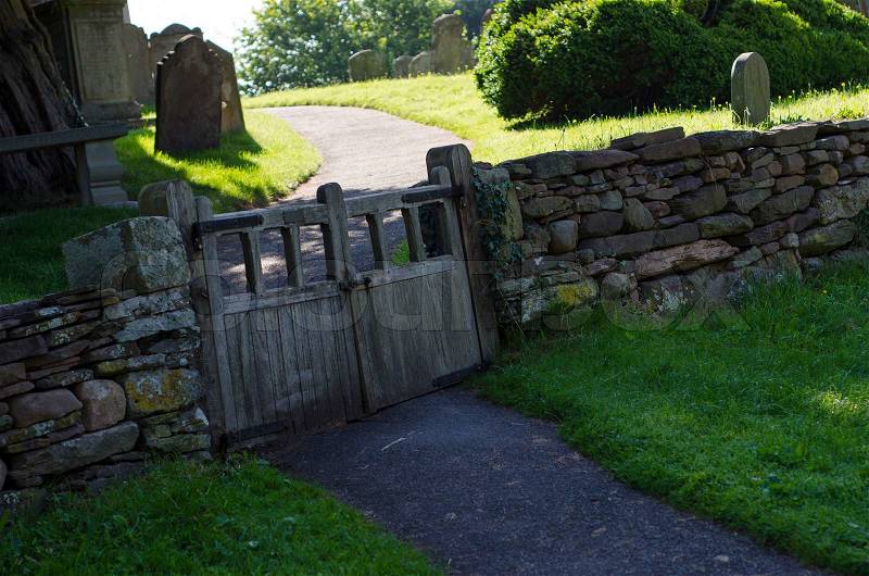 Old wooden double gate in dry stone wall to churchyard, stock photo