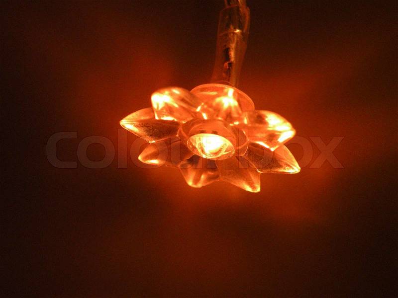 Small glowing flower lamp in darkness, stock photo