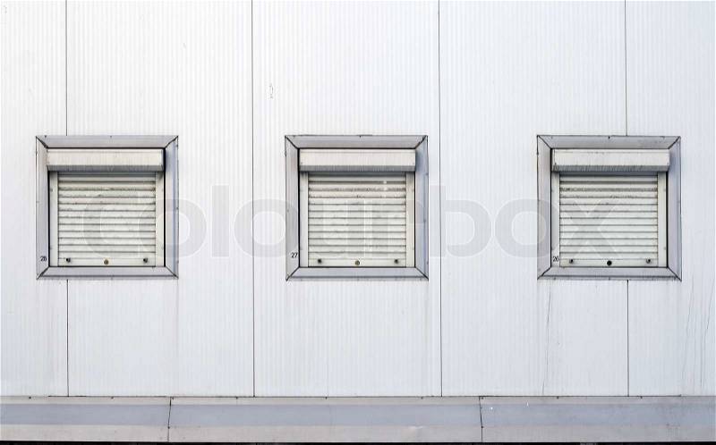 Texture of industrial building wall with three closed rectangle windows with jalousies and numeration, stock photo