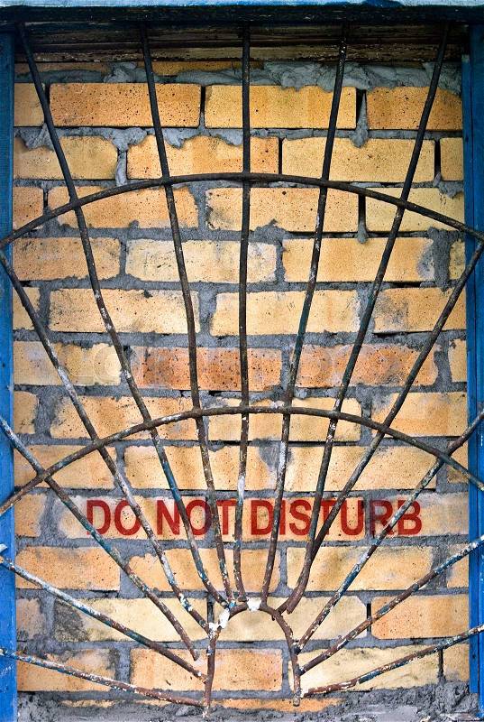 Do not disturb label on the brick-encased window with railings, stock photo