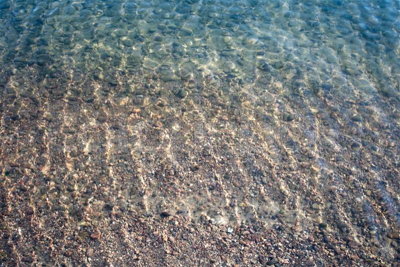 Shallow river water background texture with sand and pebbles on the ground, stock photo