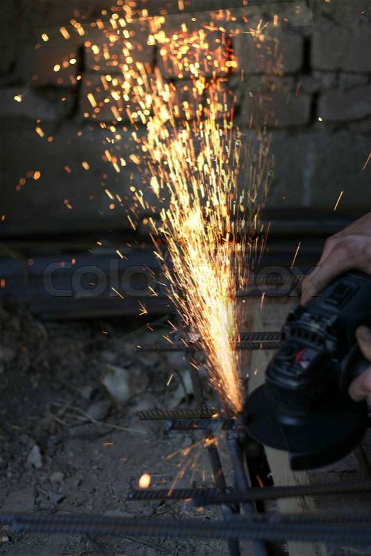 Worker cutting metal with many sharp sparks, stock photo