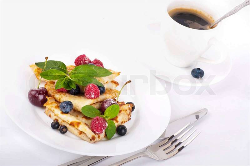 Pancakes with berries and mint and cup of coffee on a white background, stock photo
