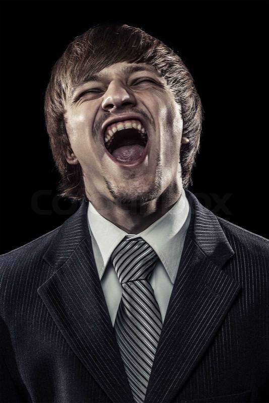 Young successful businessman laughing hard over black, stock photo