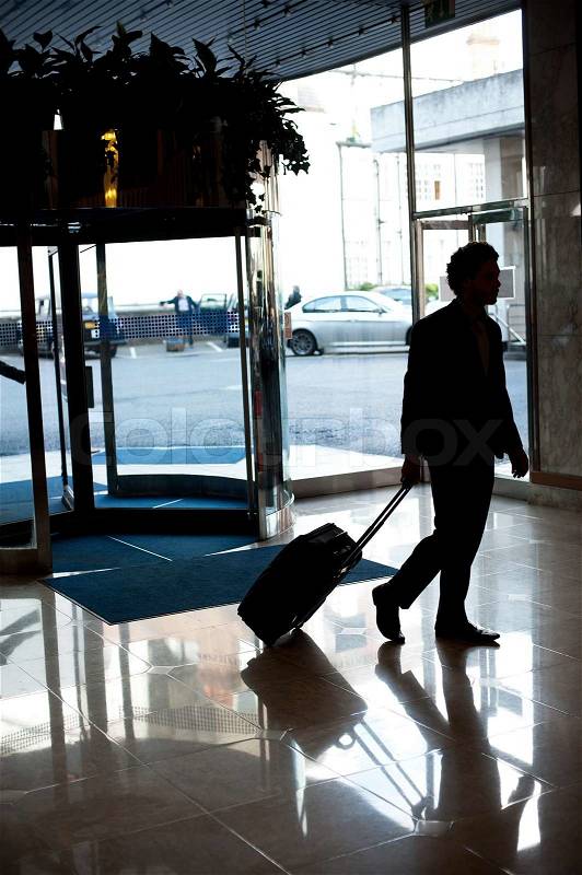 Man entering hotel lobby with his luggage, stock photo
