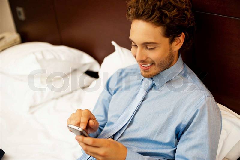 Busy young man surfing menu of his new phone, stock photo