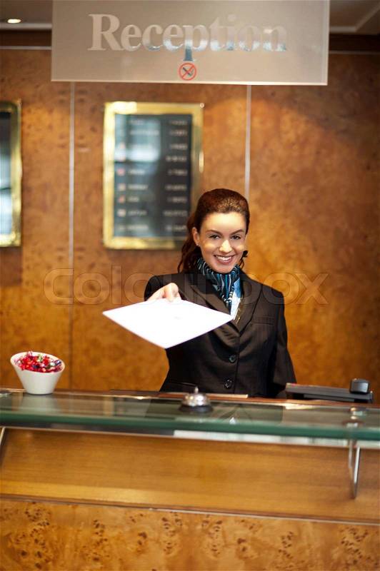 Female receptionist handing over check-out papers, stock photo