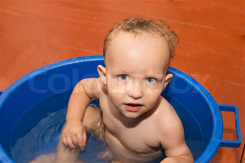 The little boy is bathed in a blue tub, stock photo