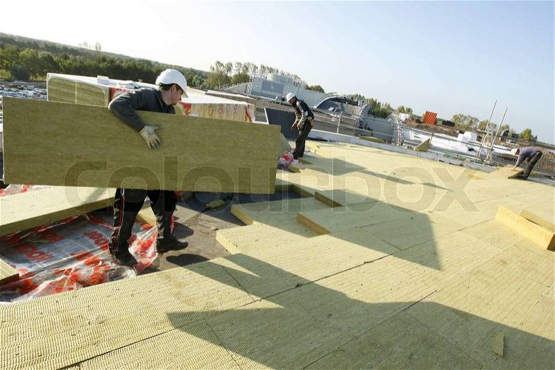 Construction workers with insulation boards on a roof of a building, stock photo