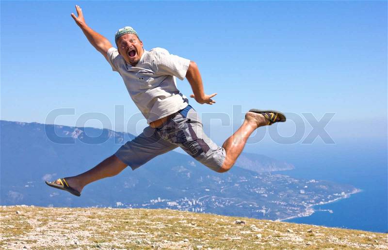 Happy man jumping on a background of mountains and sky and sea, stock photo