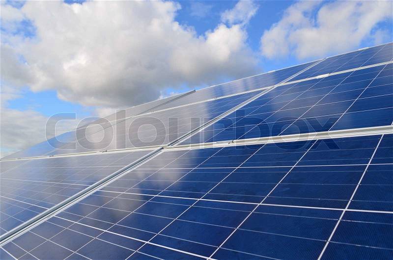 Environmental friendly Solar panels reflecting a blue sky with white clouds, stock photo