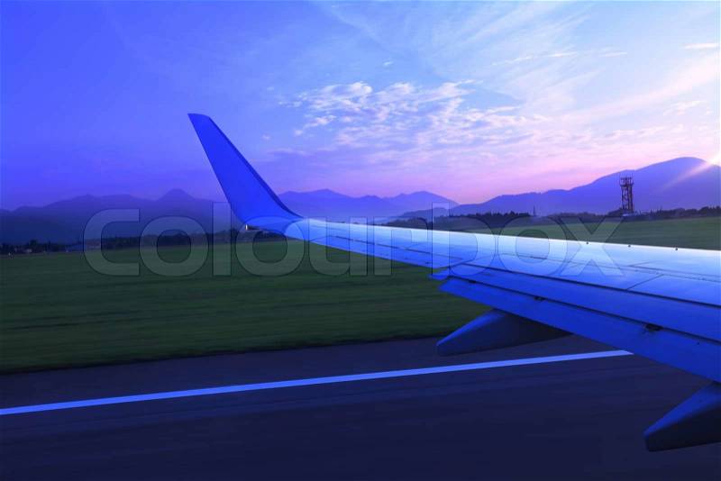 Airplane takes off from runway early morning against beautiful sunrise at Bergamo airport, Italy view from airplane window over the wing, stock photo
