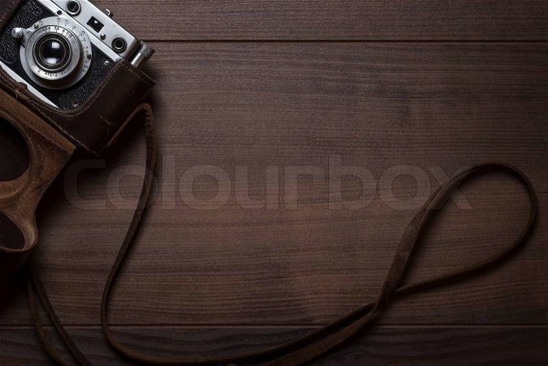 Wooden background with retro still camera in case, stock photo