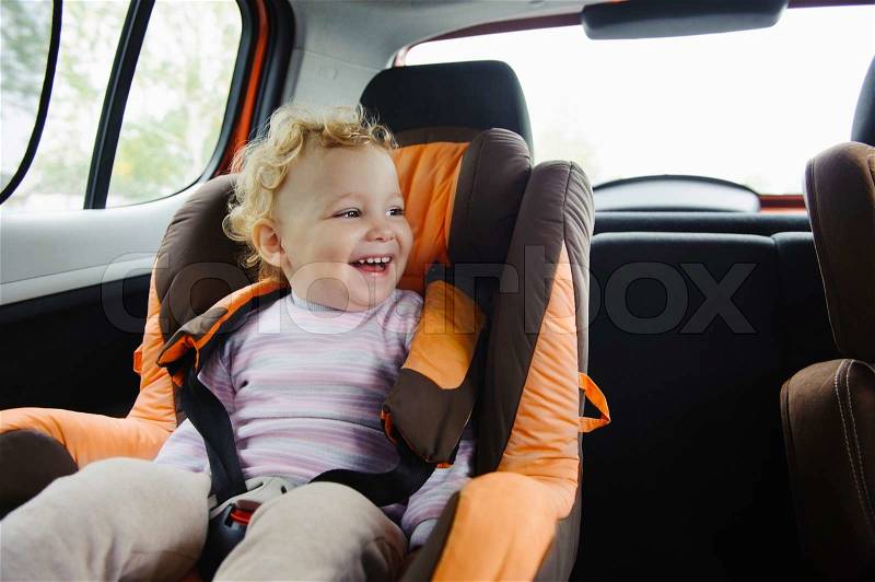 Happy child smiling in car seat, stock photo