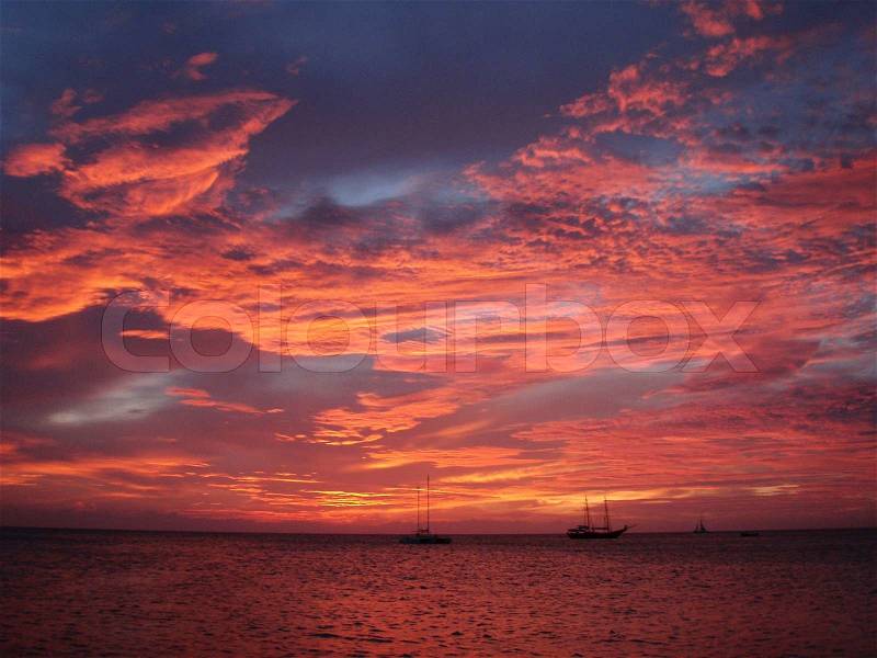 The setting sun reflecting off of intricate cloud patterns off the coast of Aruba make the sky look like an impressionist painting, stock photo