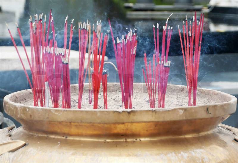 Burning incense sticks in Brass Incense Bowl at buddhist shrine, stock photo
