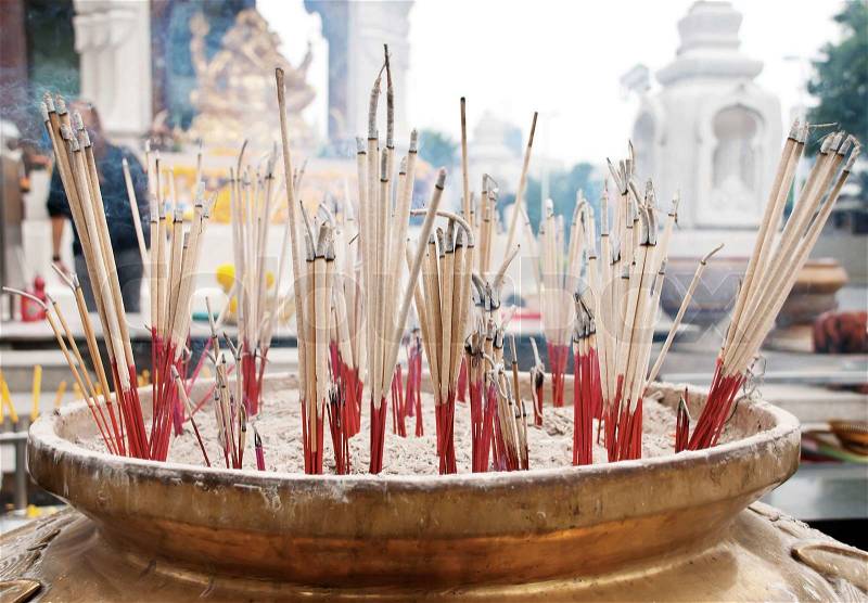 Burning incense sticks in Brass Incense bowl at buddhist shrine, stock photo