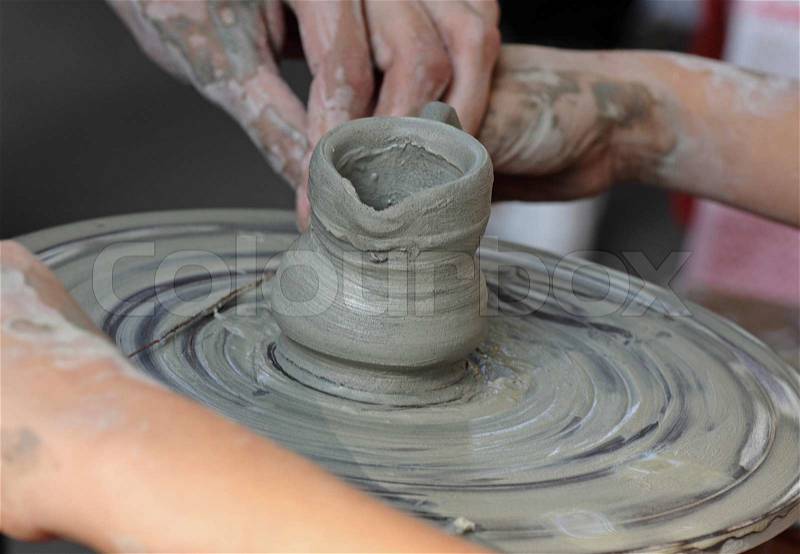 Potter teaching child how to make a jar on a potter's wheel, stock photo