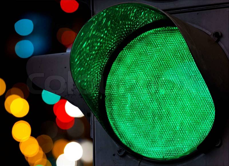 Green traffic light with colorful unfocused lights on a background, stock photo