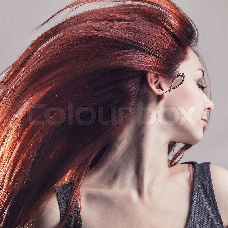 Girl with flying hair over grey background, stock photo