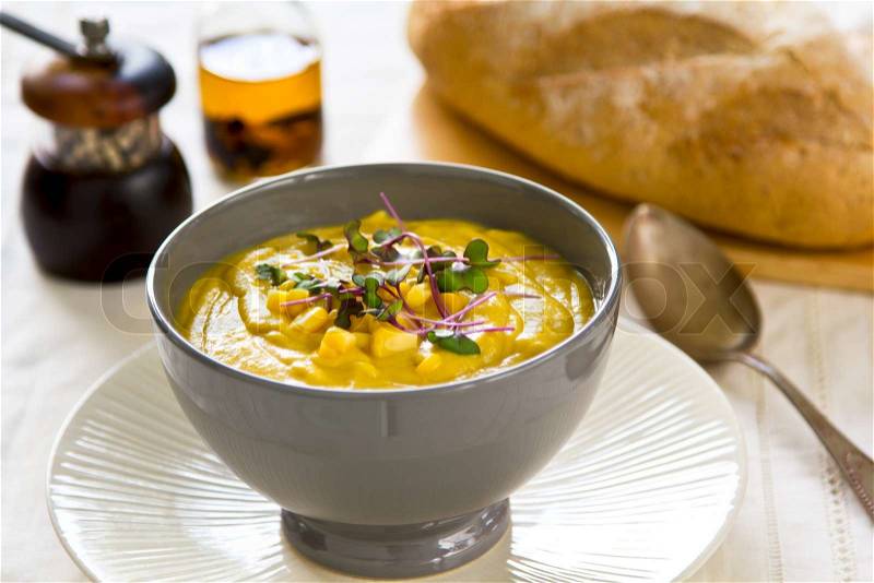 Corn soup with fresh corn and purple sprout on top by loaf of bread, stock photo