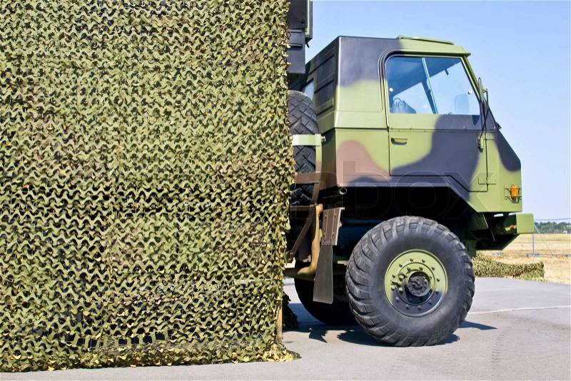 Military vehicle hung with camouflage netting, stock photo