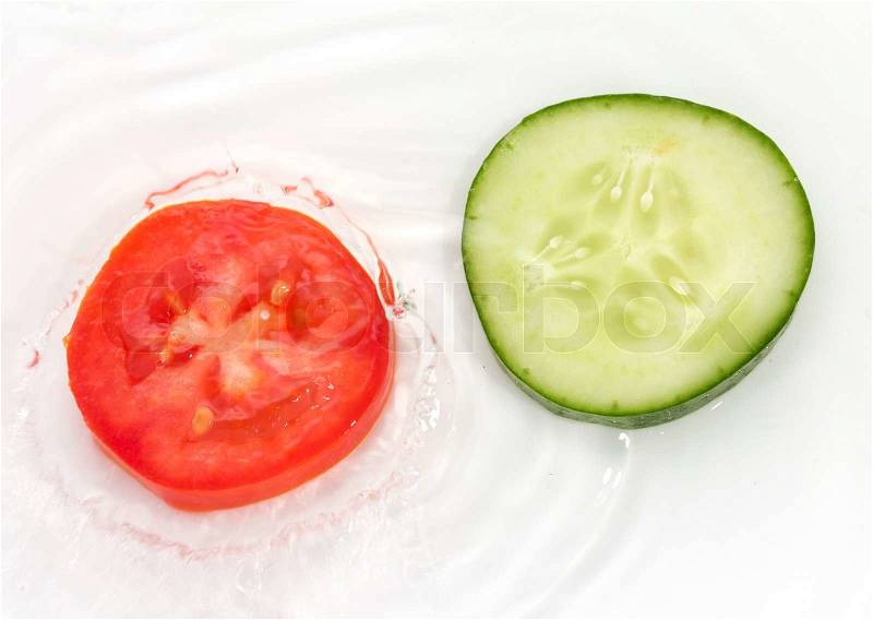 Cucumber and tomato in water on white background, stock photo