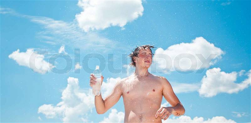 Young exhausted athlete splashing and pouring fresh water on his head to refresh during a running trail, stock photo