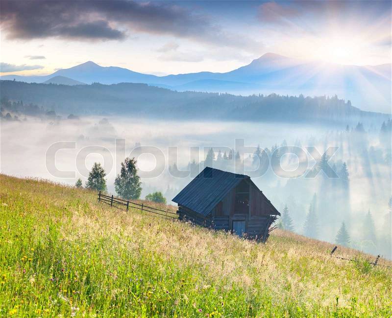 Foggy landscape with an old barn in the mountains at the summer, stock photo