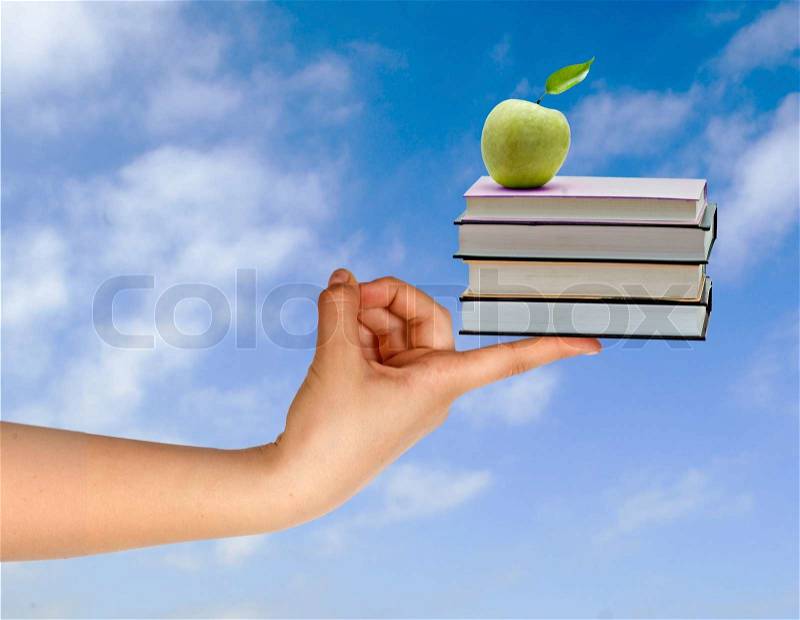 Books with apple on finger as a gift of education, stock photo