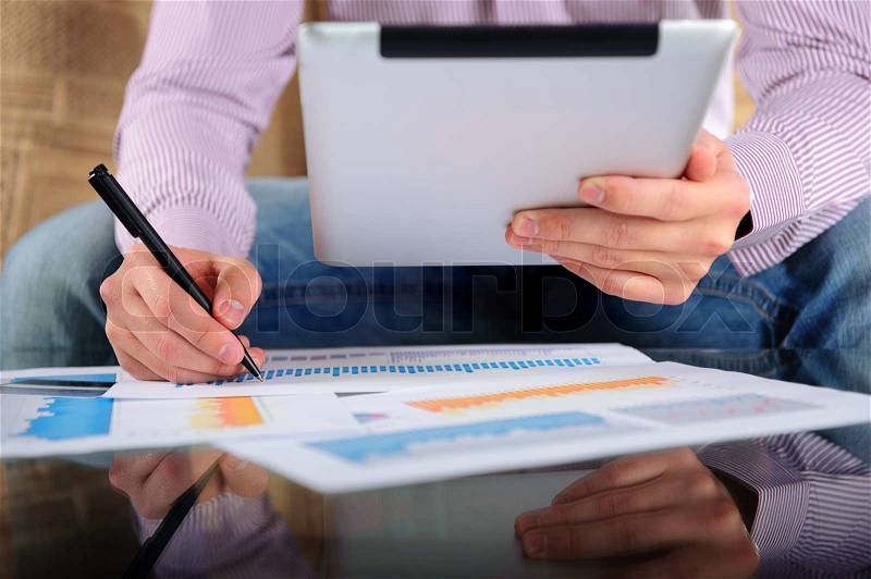Young businessman analyzing charts with digital tablet, stock photo