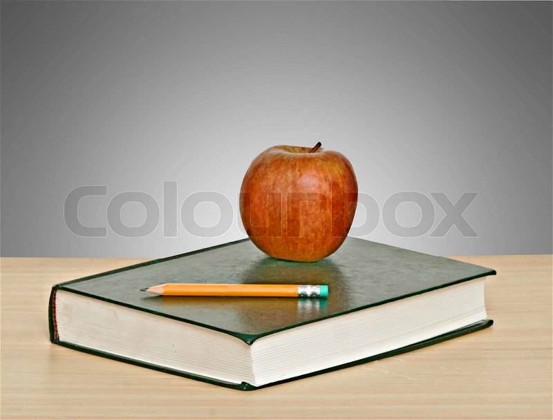 Red apple and pencil on top of book, stock photo